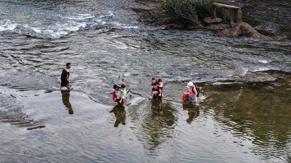 Cõng con qua sông đến trường