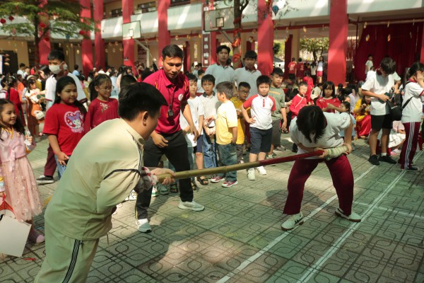 Học sinh chơi đẩy gậy, khắc dưa hấu, làm bánh đón tết ở sân trường